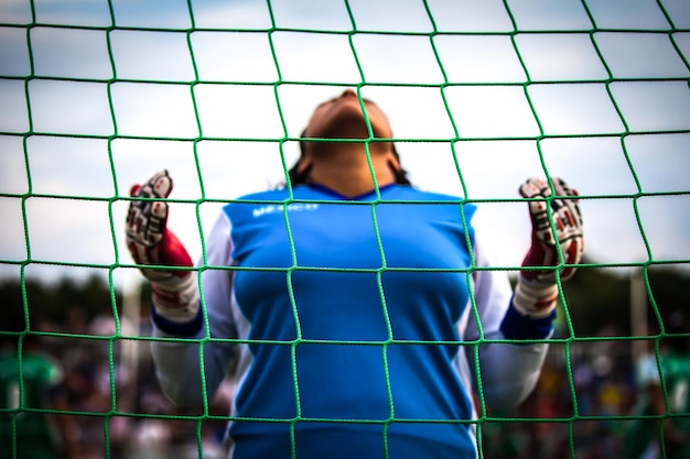 Vista de ângulo baixo de mulher vista através da rede no campo de futebol