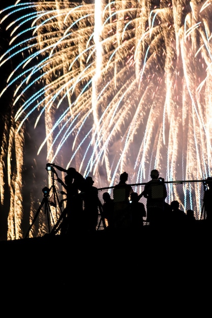 Foto vista de ângulo baixo de pessoas em silhueta contra fogos de artifício à noite