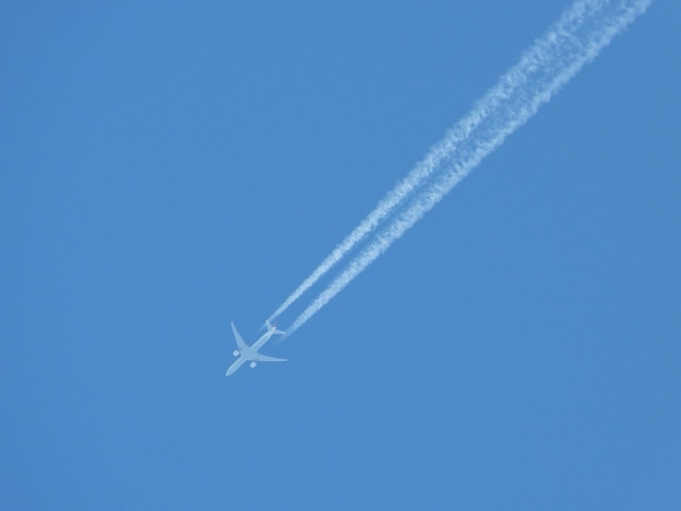 Foto vista de ângulo baixo de trilhas de vapor contra um céu azul claro