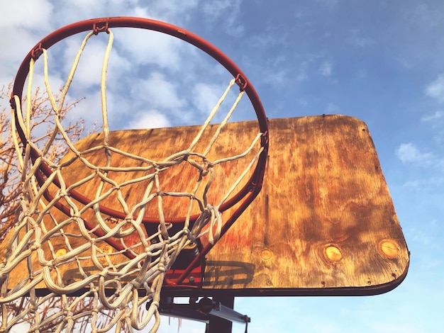 Vista de ângulo baixo de um aro de basquete caseiro contra o céu