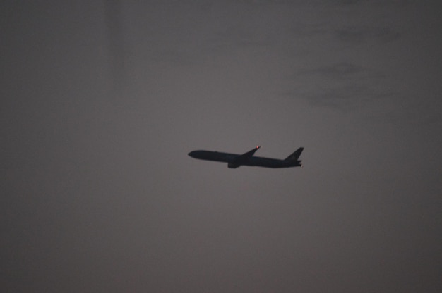 Foto vista de ângulo baixo de um avião de silhueta voando contra o céu