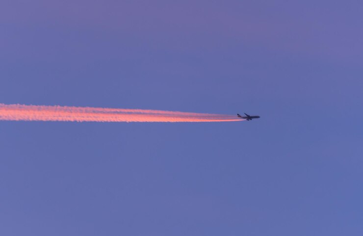 Foto vista de ângulo baixo de um avião voando contra um céu azul claro