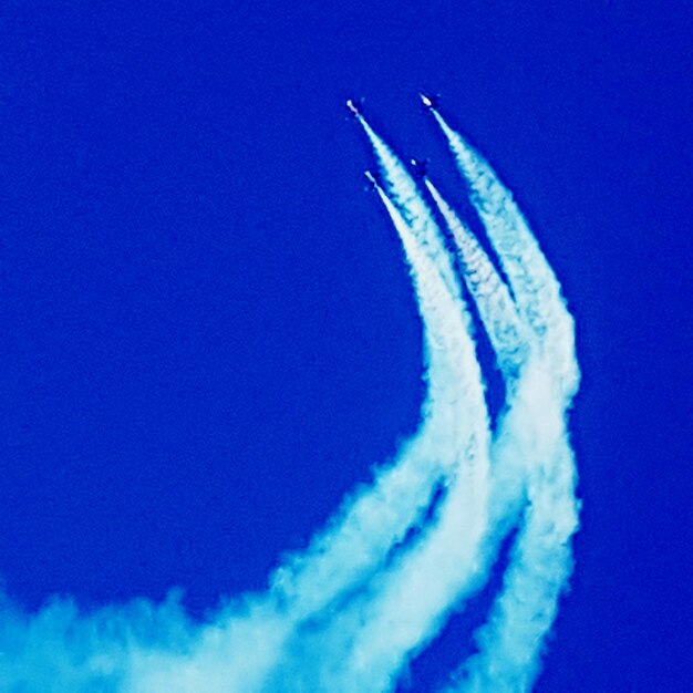 Foto vista de ângulo baixo de um avião voando contra um céu azul claro