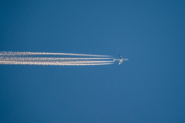 Foto vista de ângulo baixo de um avião voando contra um céu azul claro