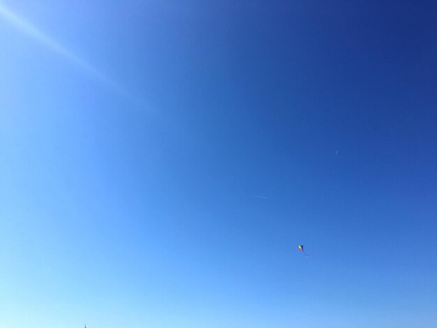 Vista de ângulo baixo de um avião voando contra um céu azul claro