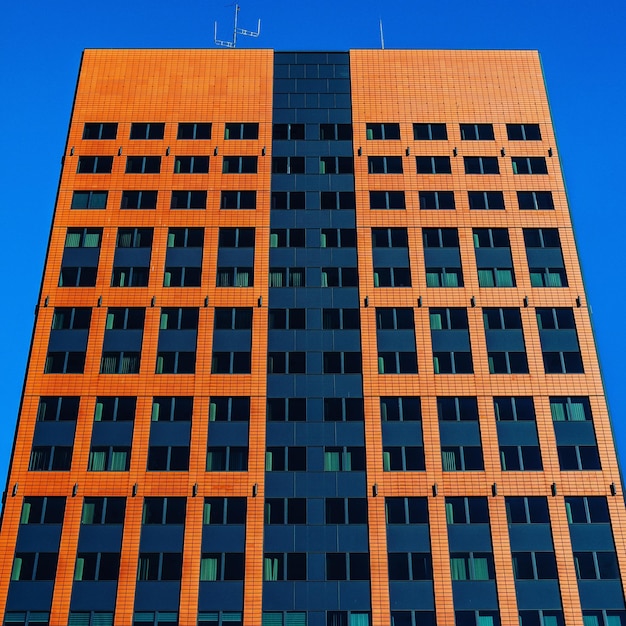 Foto vista de ângulo baixo de um edifício moderno contra um céu azul claro