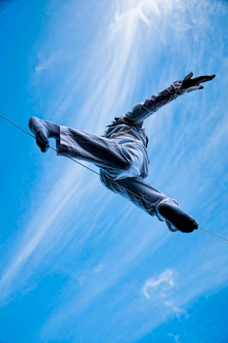 Foto vista de ângulo baixo de um homem caminhando em corda contra o céu azul