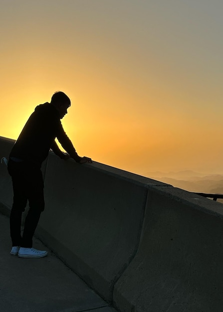 Foto vista de ângulo baixo de um homem de pé contra o céu durante o pôr do sol