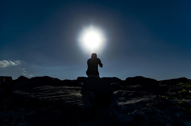 Foto vista de ângulo baixo de um homem em silhueta contra o céu azul em um dia ensolarado