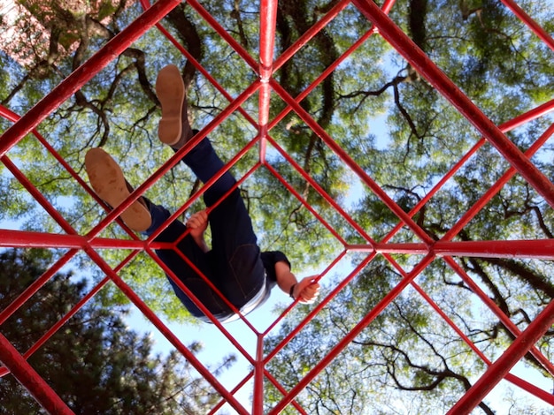 Vista de ângulo baixo de um homem em uma estrutura metálica no parque