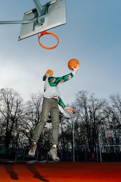 Vista de ângulo baixo de um homem jogando basquete contra o céu