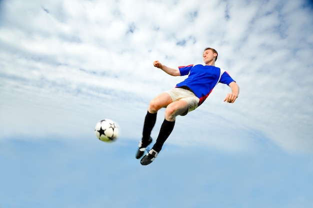 Vista de ângulo baixo de um homem jogando bola de futebol contra o céu