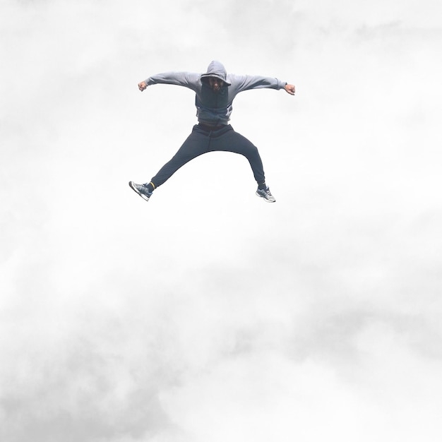 Foto vista de ângulo baixo de um homem pulando contra o céu