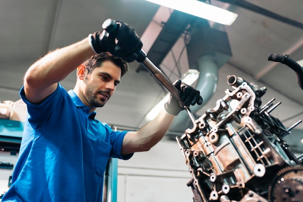 Foto vista de ângulo baixo de um mecânico reparando o motor na garagem