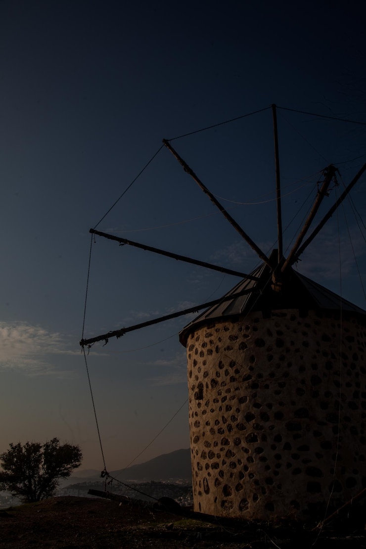 Foto vista de ângulo baixo de um moinho de vento tradicional contra o céu ao pôr-do-sol
