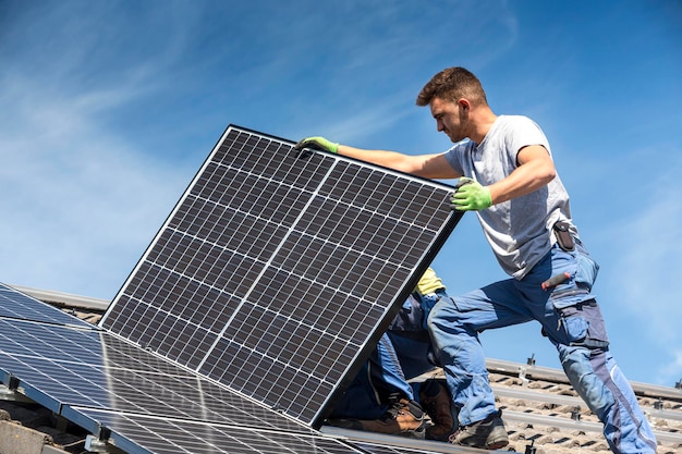 Vista de ângulo baixo de um trabalhador instalando painel solar no telhado contra o céu