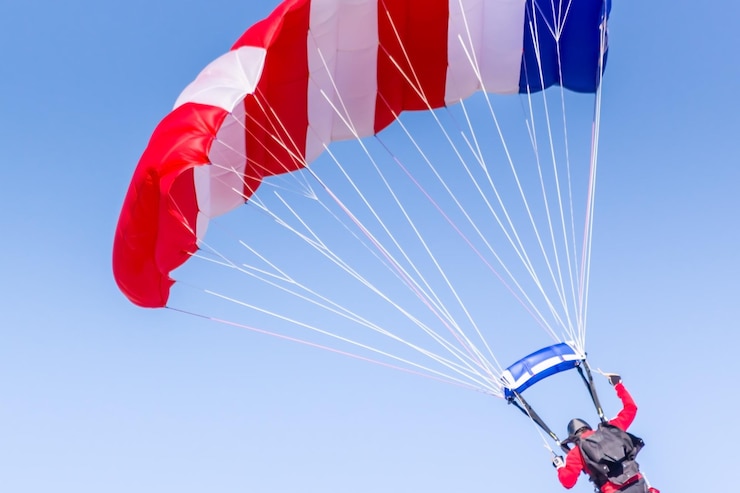 Foto vista de ângulo baixo de uma pessoa em parapente contra o céu azul
