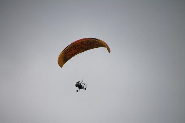 Vista de ângulo baixo de uma pessoa em parapente contra um céu claro