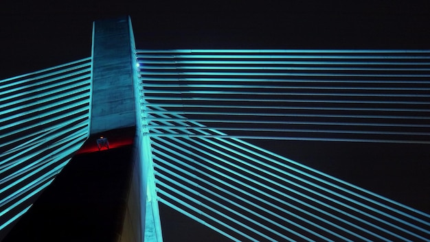 Vista de ângulo baixo de uma ponte iluminada contra um céu claro à noite