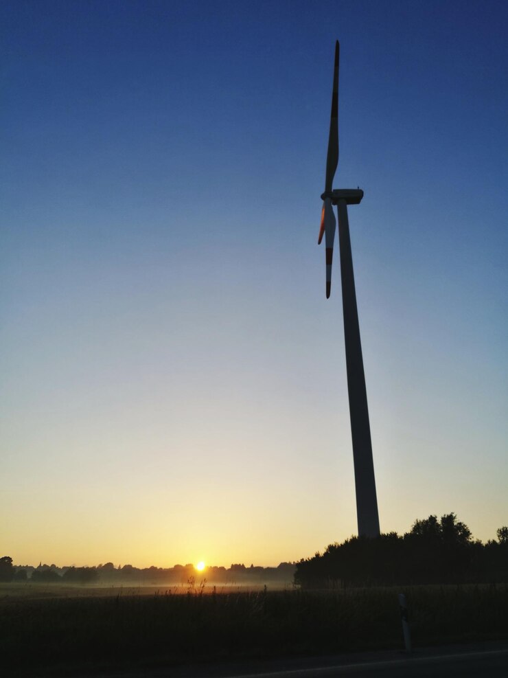 Foto vista de ângulo baixo do moinho de vento no campo contra o céu durante o pôr do sol