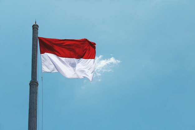 Foto vista de baixo ângulo da bandeira indonésia contra o céu azul