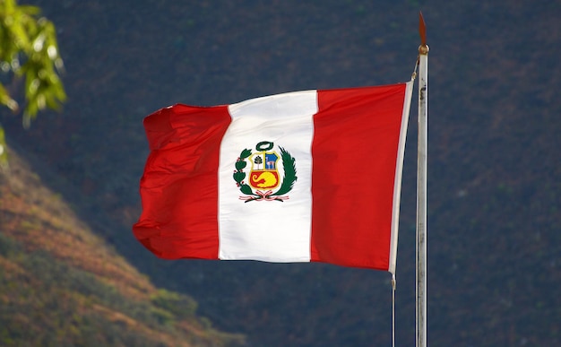 Vista de baixo ângulo da bandeira peruana ondulando contra as montanhas