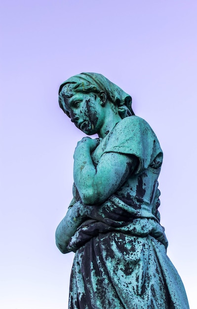 Foto vista de baixo ângulo da estátua desgastada contra o céu claro