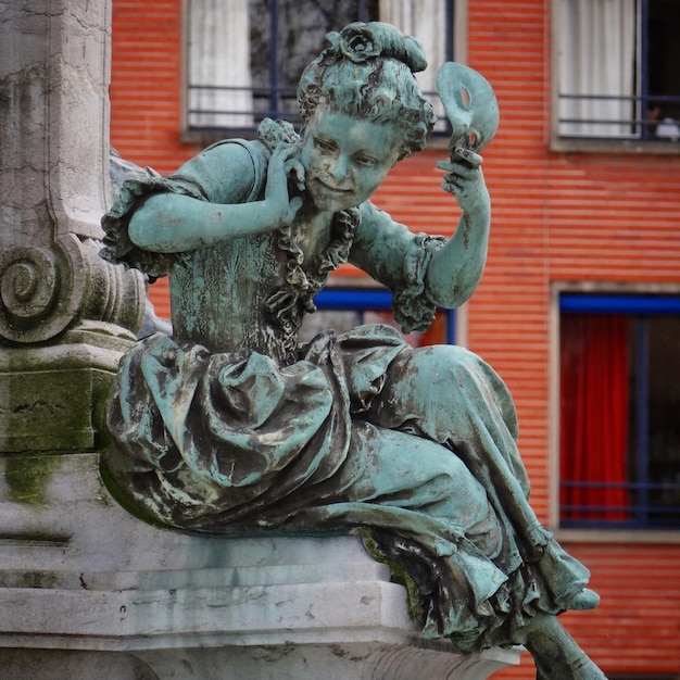 Vista de baixo ângulo da estátua feminina contra o edifício