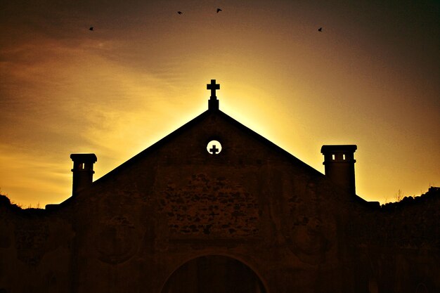 Foto vista de baixo ângulo da igreja contra o céu durante o pôr do sol