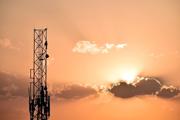 Foto vista de baixo ângulo da torre de comunicações de silhueta contra o céu durante o pôr do sol