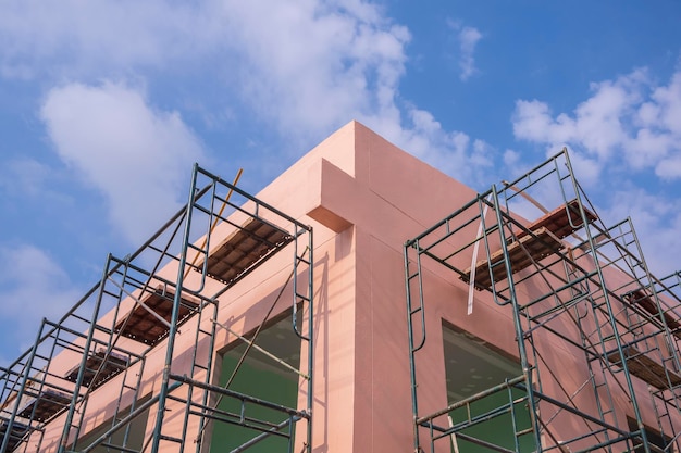 Foto vista de baixo ângulo de andaimes na parede rosa fora da estrutura de construção de casas no canteiro de obras