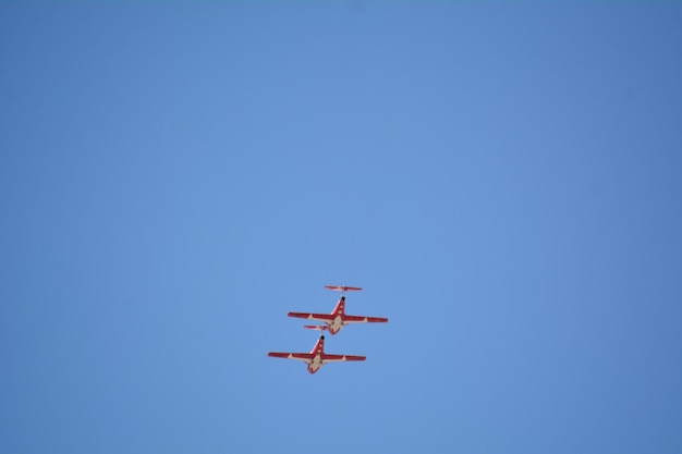 Foto vista de baixo ângulo de duas aeronaves voando em formação contra um céu azul claro