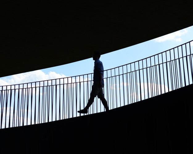 Vista de baixo ângulo de homem em silhueta na ponte contra o céu