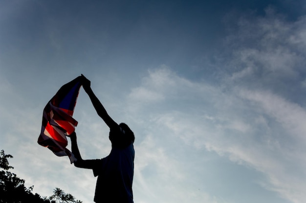 Foto vista de baixo ângulo de homem segurando bandeira americana contra o céu