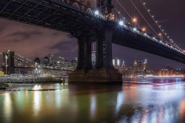 Foto vista de baixo ângulo de manhattan e da ponte de brooklyn sobre o east river à noite