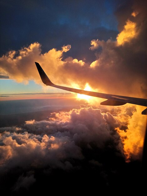 Foto vista de baixo ângulo de um avião de silhueta voando contra o céu durante o pôr do sol