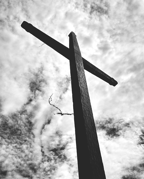 Foto vista de baixo ângulo de uma cruz de madeira contra um céu nublado