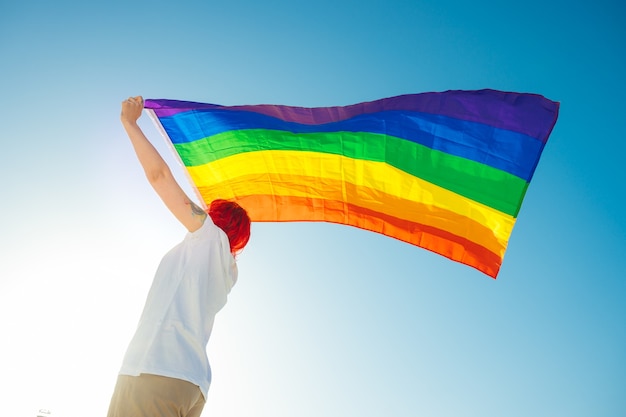 Vista de baixo ângulo de uma jovem segurando uma bandeira LGBT durante a parada do orgulho