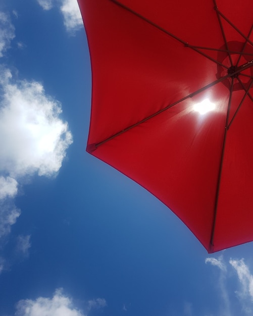 Vista de baixo ângulo do guarda-chuva vermelho contra o céu