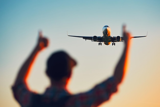 Vista de baixo ângulo do homem fazendo gestos para o avião contra o céu