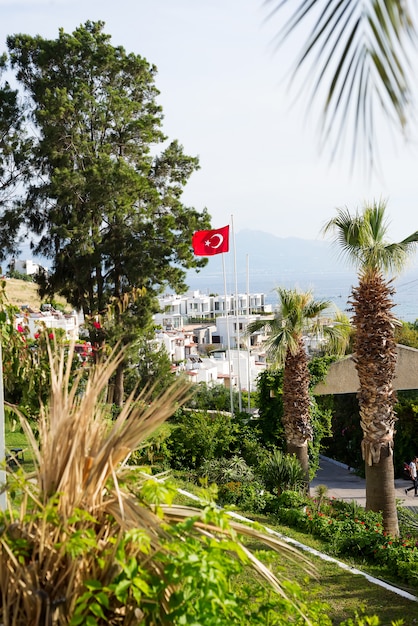 Vista de Bodrum sity, palmeiras, mar e a bandeira da Turquia