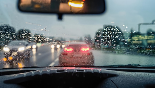 Vista de carros de trânsito e luzes de dentro de um carro em um dia chuvoso