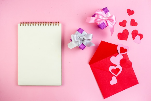 vista de cima adesivos de coração vermelho envelopes de caderno vermelho presentes em fundo rosa