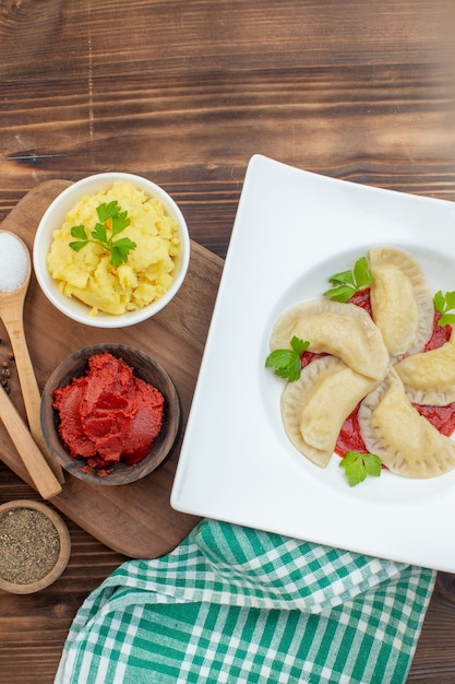 vista de cima bolinhos quentes de batata com pasta de tomate e temperos em um fundo de madeira marrom