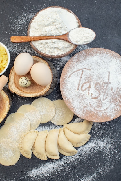 Vista de cima bolinhos quentes de batata crua com ovos batidos de batata e farinha no fundo escuro refeição torta biscoito forno assar massa cozinhar