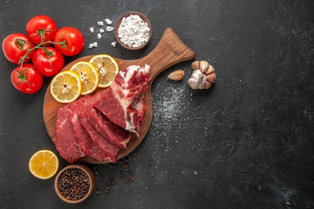 Vista de cima carne fresca fatiada com rodelas de limão e tomate vermelho