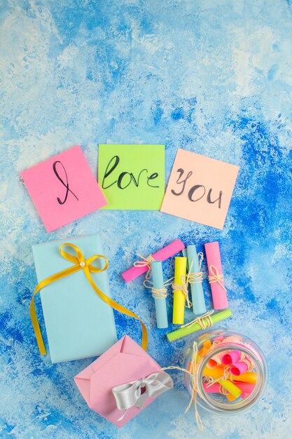 Foto vista de cima conceito de dia dos namorados eu te amo escrito em notas adesivas coloridas role papéis de desejo em presentes de frasco na mesa