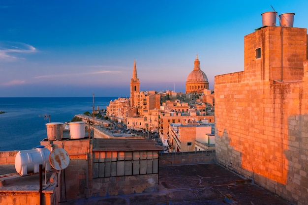 Vista de cima das cúpulas de igrejas e telhados no belo pôr do sol com a Igreja de Nossa Senhora do Monte Carmelo e Pró-Catedral Anglicana de São Paulo, Valletta, capital de Malta