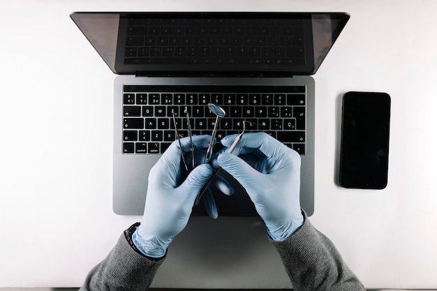 Foto vista de cima das mãos do médico com suas ferramentas de trabalho e laptop cinza