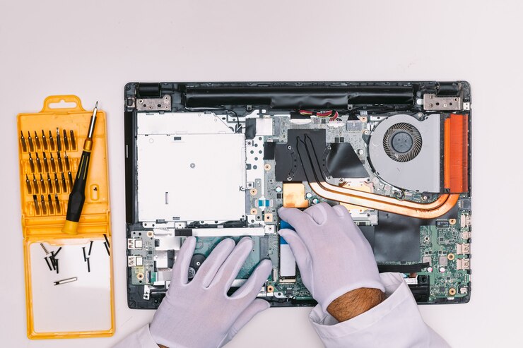 Vista de cima das mãos enluvadas de um engenheiro, colocando um disco rígido SSD em um laptop em uma mesa branca